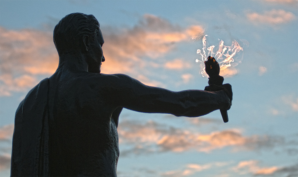The torchbearer at Circle Park is silhouetted against a sunset with blue skies